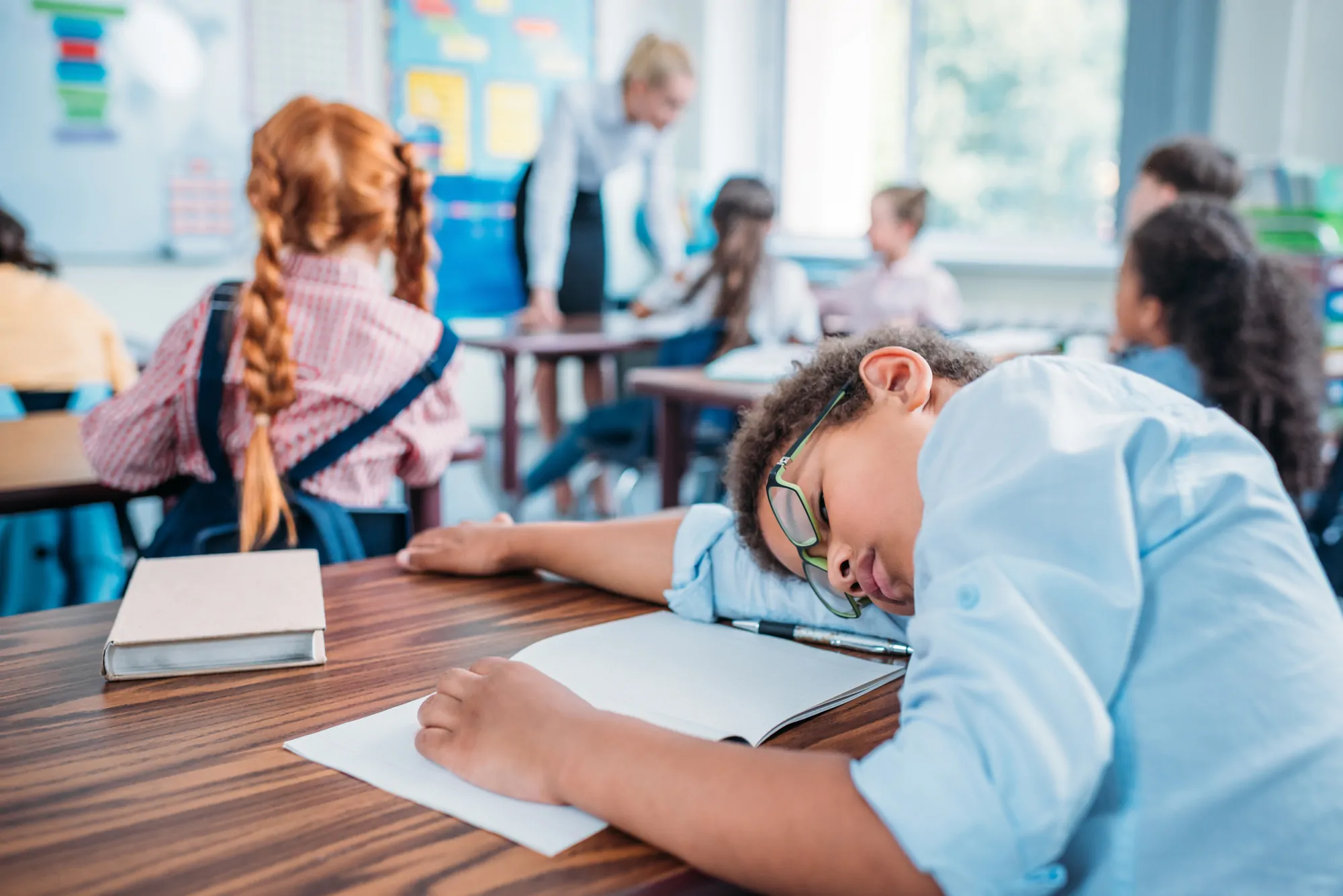 young boy fallen asleep in class with his head on the desk