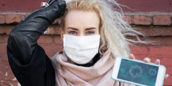 The girl shows on the phone the structure of the virus in a protective medical mask