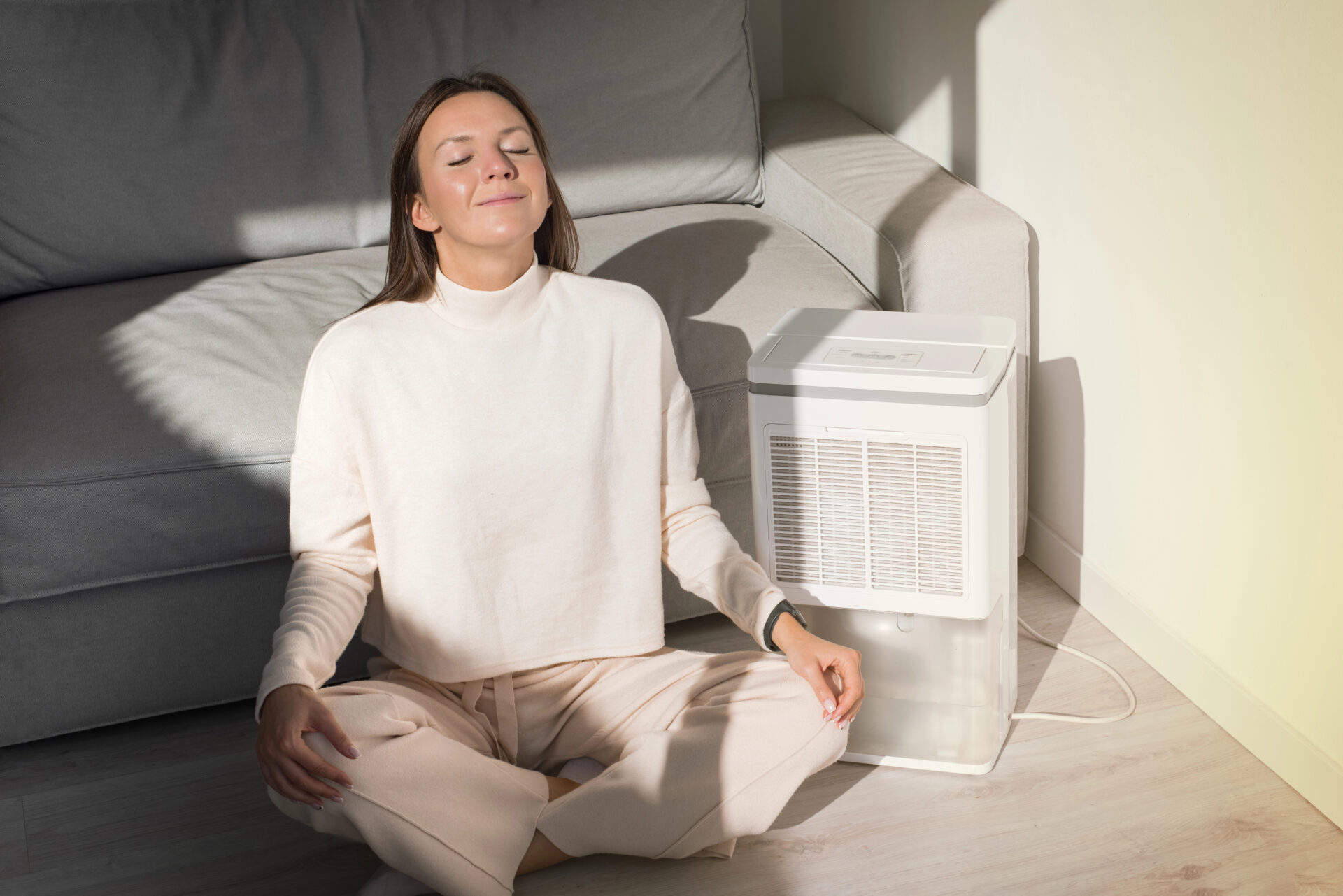 Woman sitting in front of her air purifier and breathing easy