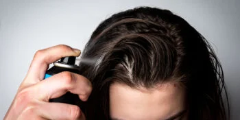 Woman sprays dry shampoo with toxic benzene in her hair