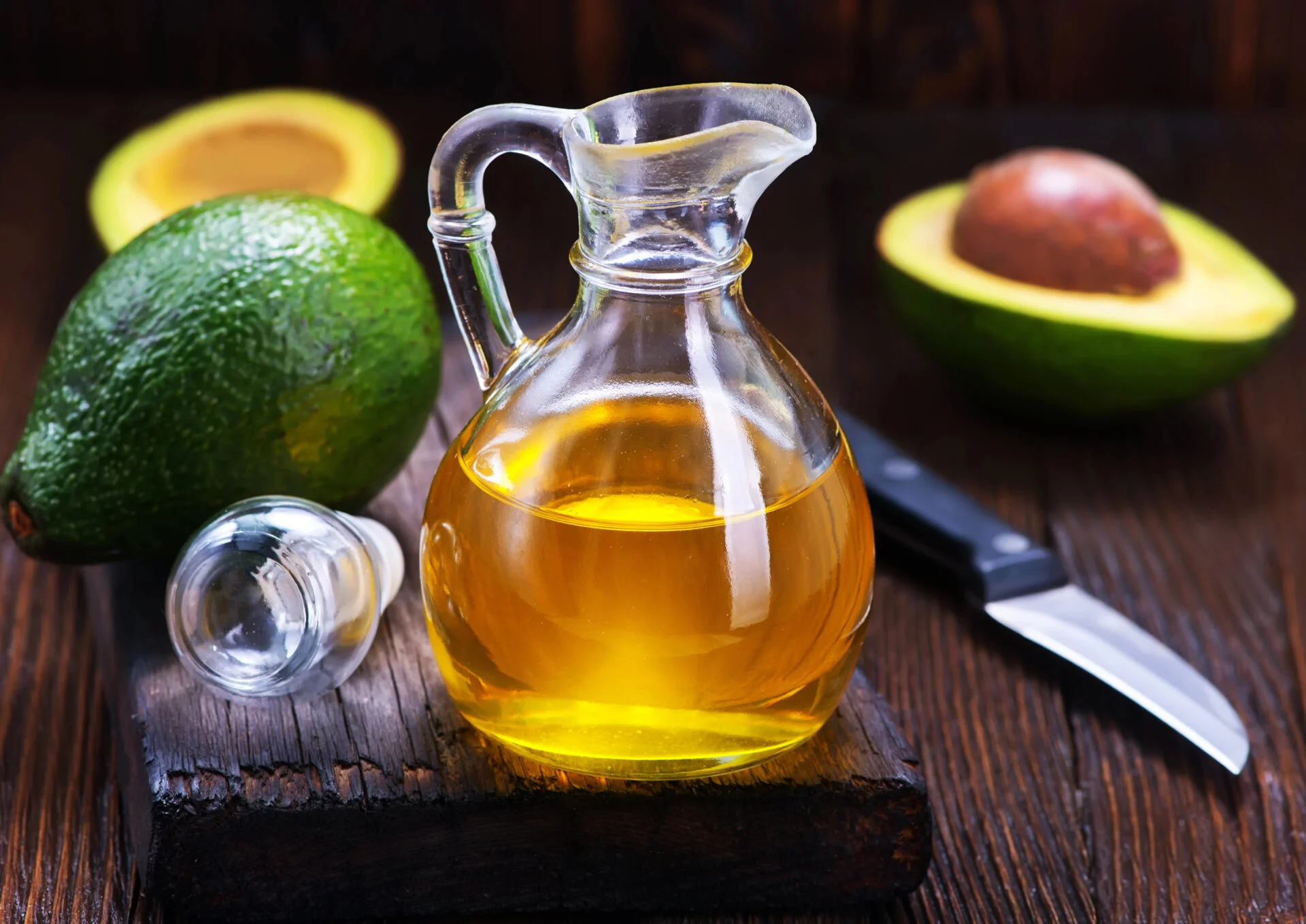 Avocado oil with a paring knife on a dark wooden table