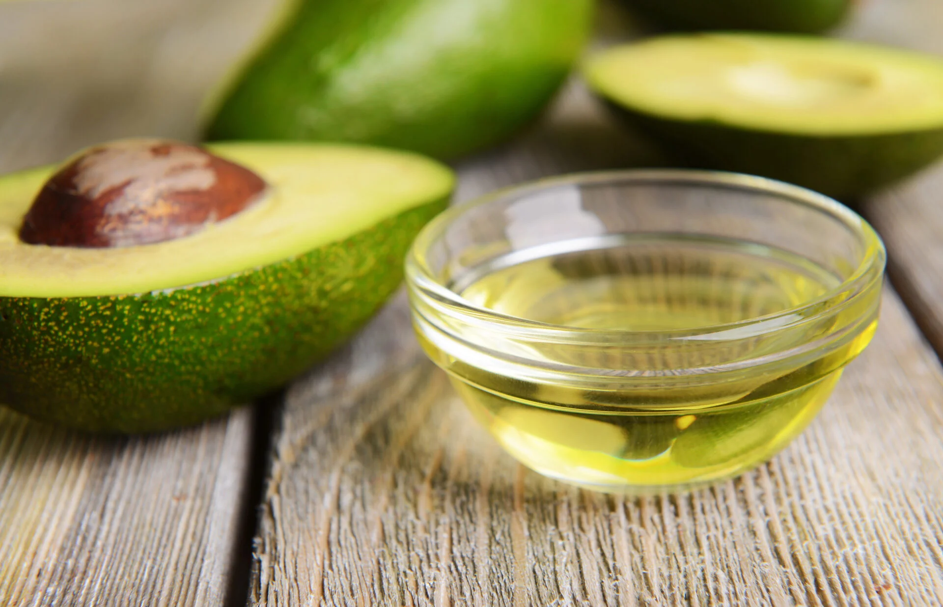 Avocado halves with avocado oil inside a glass ramekin