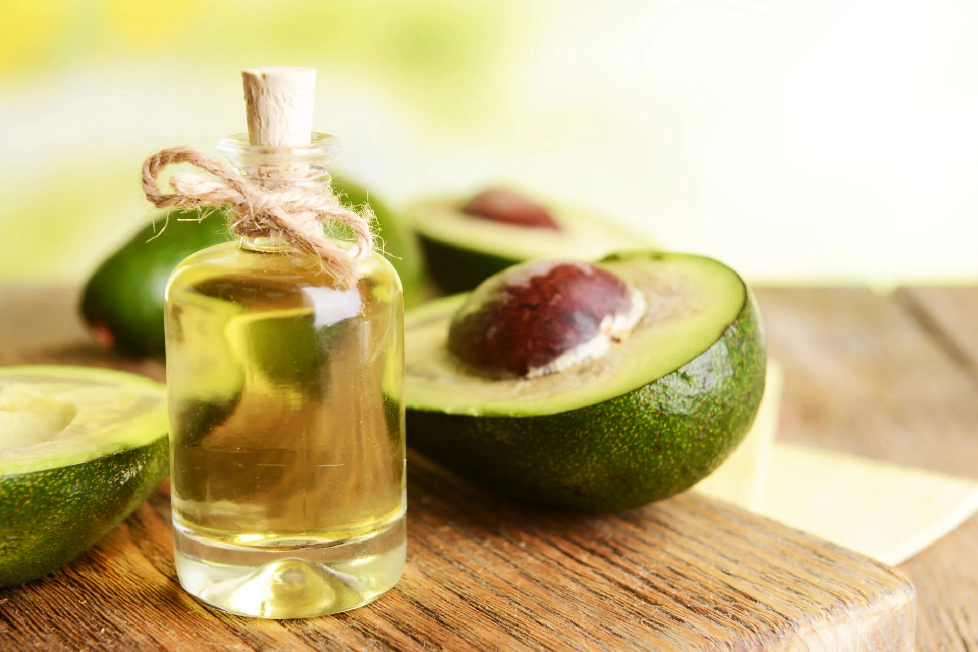 Avocado Oil on a table with avocados next to it