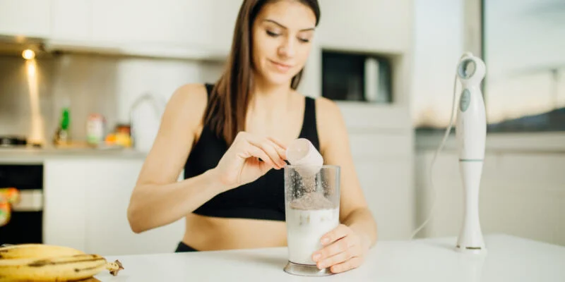 Woman with immersion blender making a chocolate protein powder smoothie