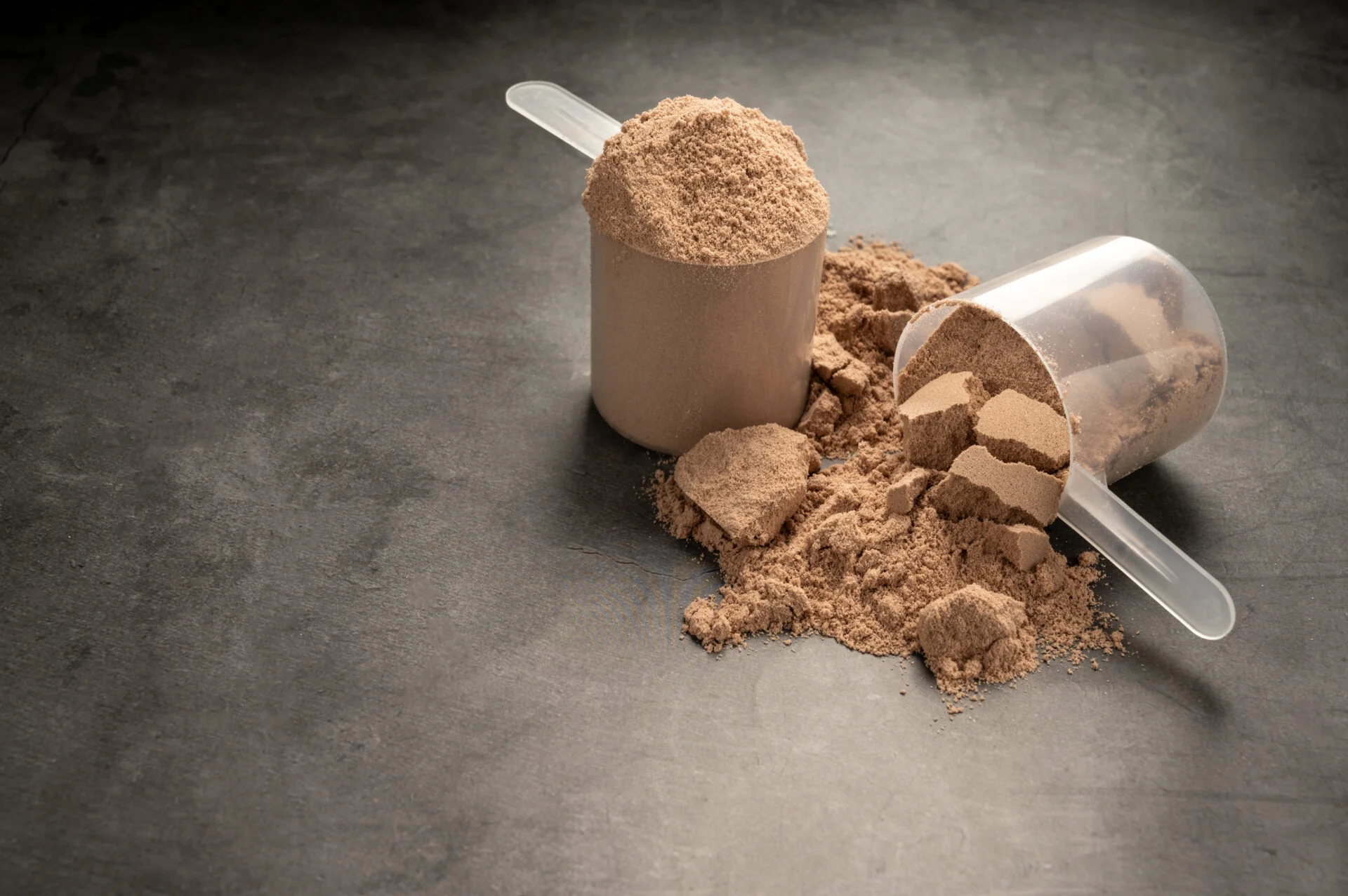 Chocolate protein powder in scoops. Food supplement, nutrition.