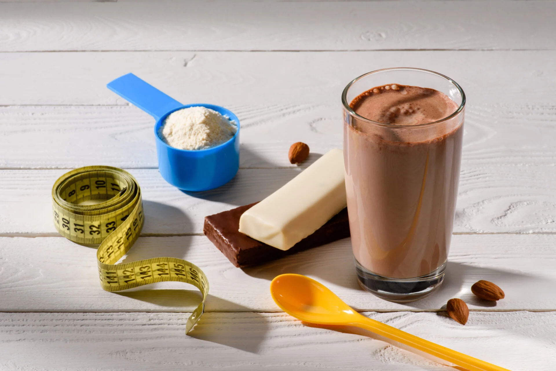 Chocolate protein powders on a white wooden table with other objects