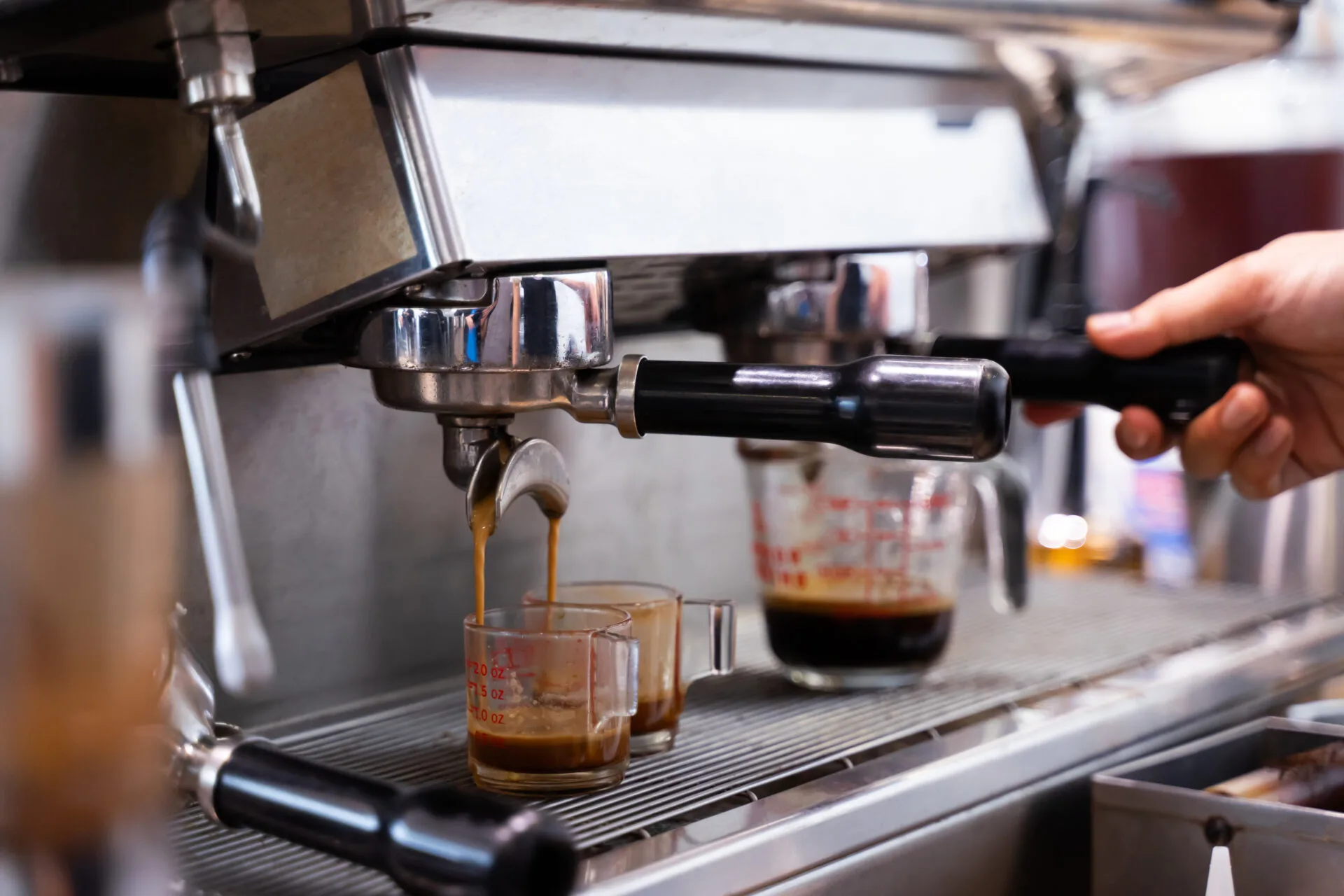 The barista makes latte art coffee with an espresso machine.