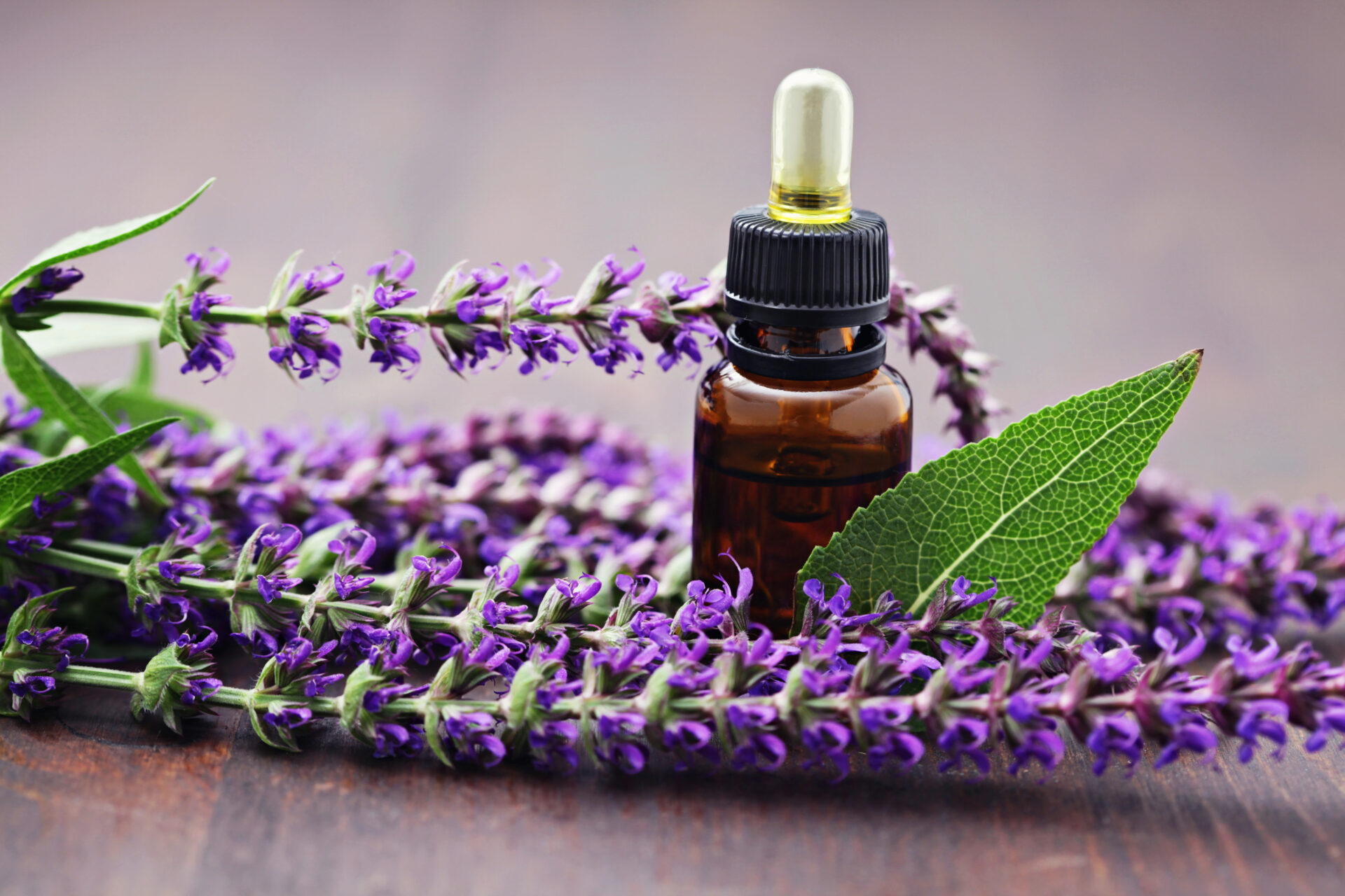 lavender essential oil on a wooden table with lavender next to it