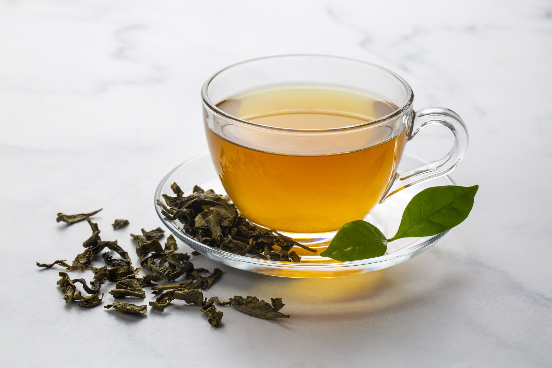 Cup of healthy green tea with tea leaves.