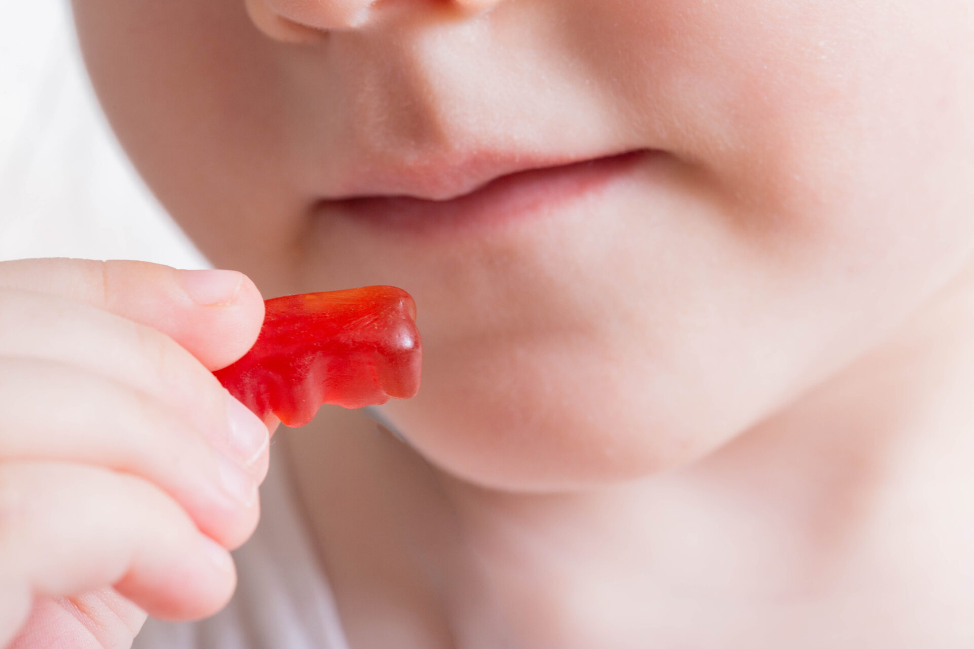 A little girl eats a vitamin in the form of a bear. The concept of strengthening children's health with multivitamin complexes. Close-up, delicious, vitamin