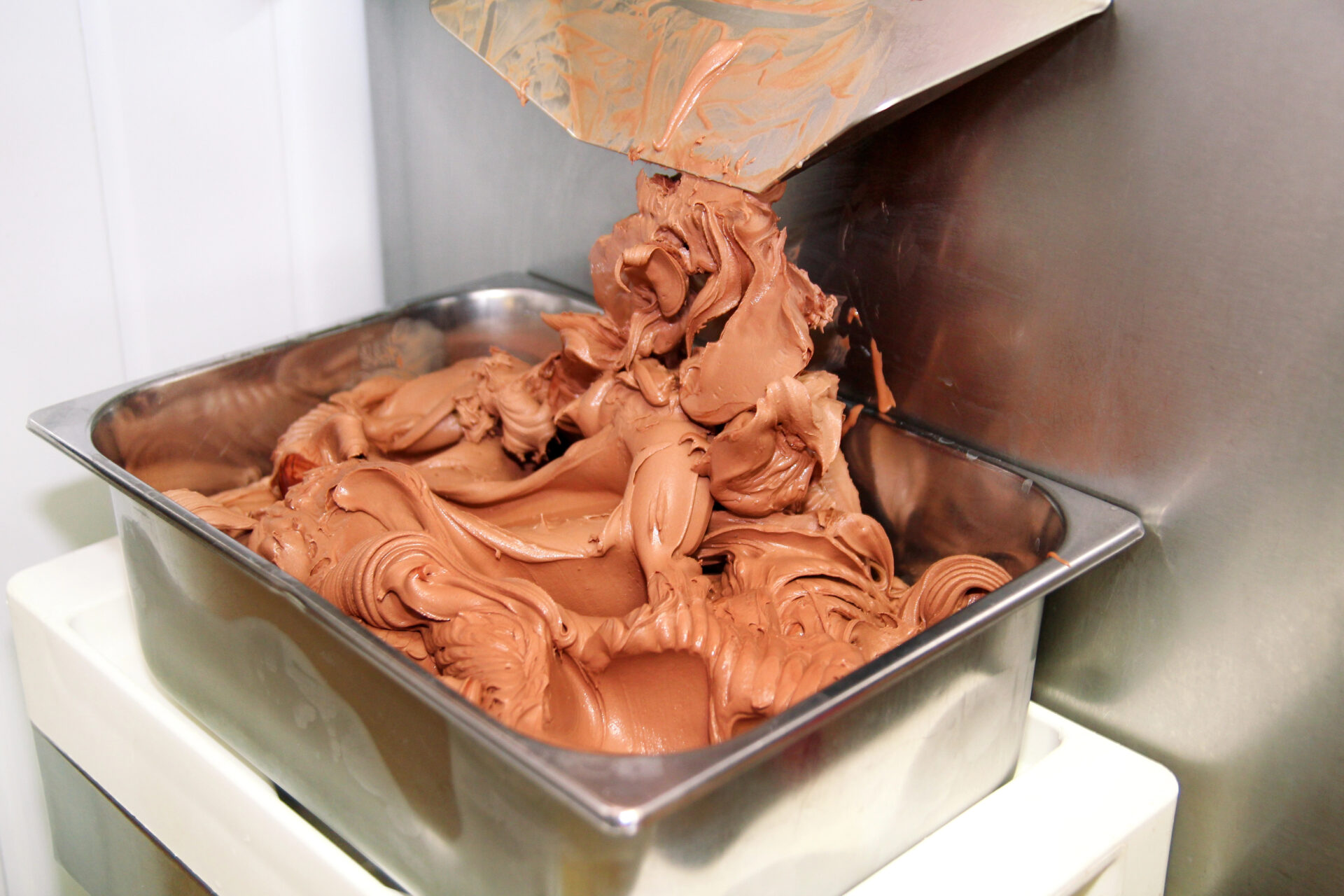 Chocolate ice cream being held in a rectangular stainless steel container