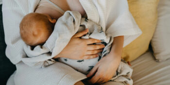 Redhead baby laying on moms lap as she lounges in her robe