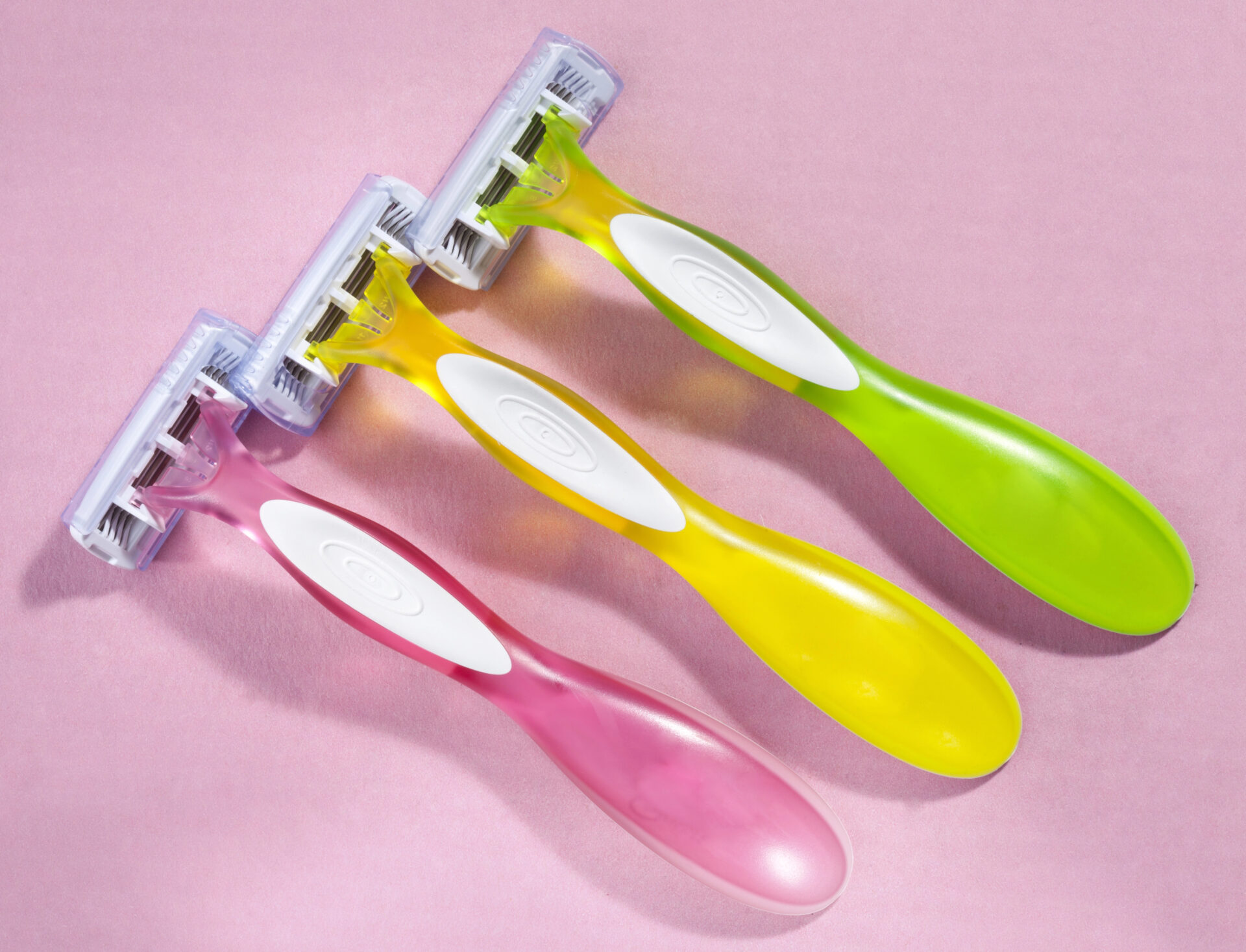 Razors coated in PTFE, a type of teflon, on a pink background