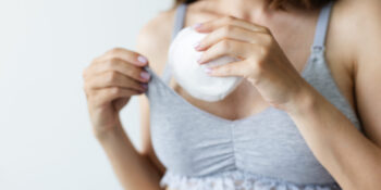 Woman putting in bra the absorbent pad. Selective focus.