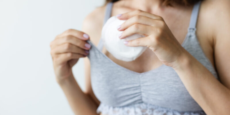 Woman putting in bra the absorbent pad. Selective focus.