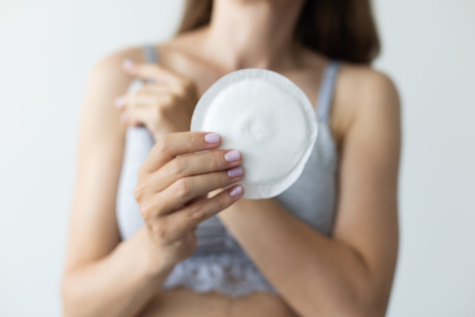 Woman holding absorbent pad for breast. Closeup, selective focus