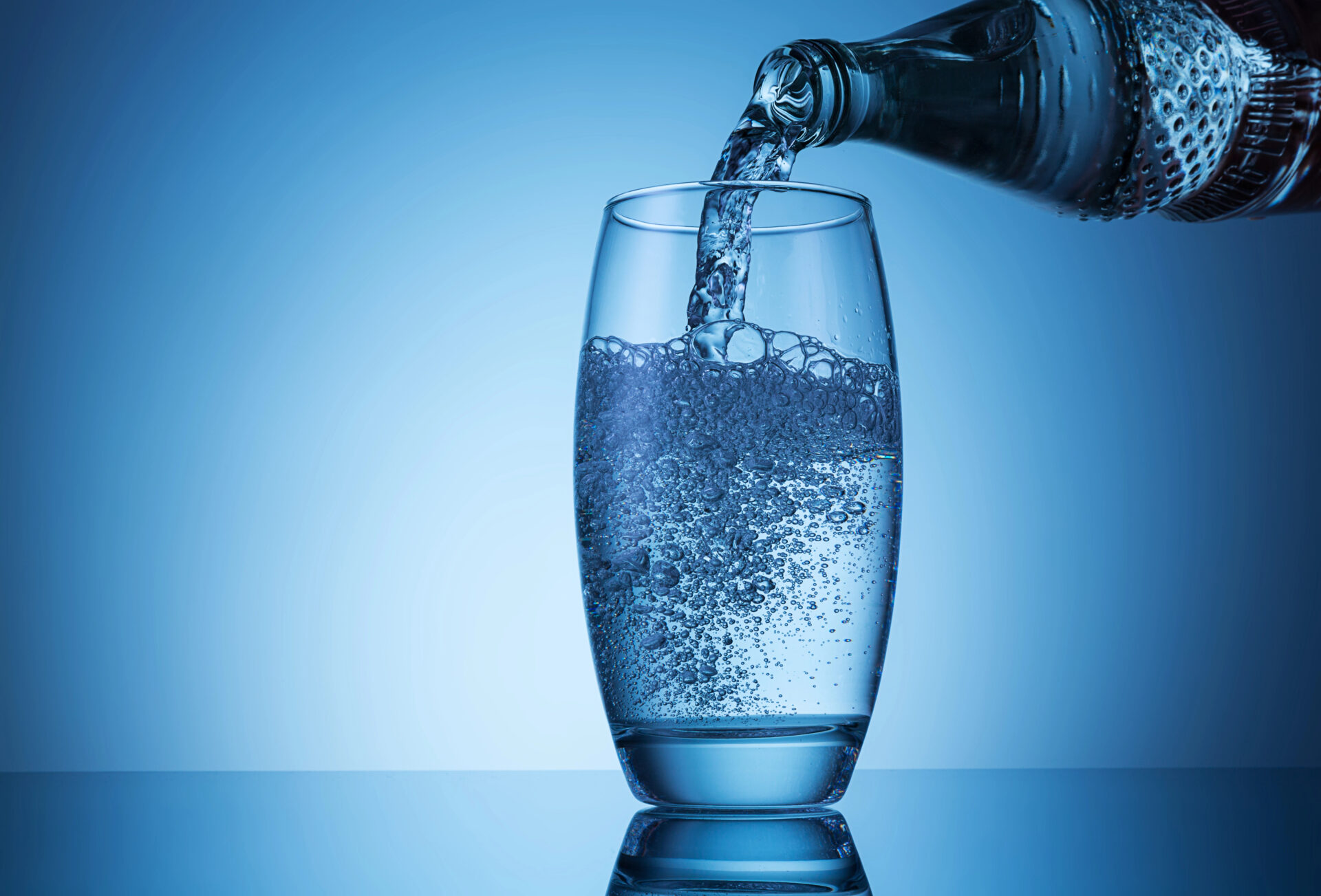 Seltzer water tested for PFAS "forever chemicals" being poured on the table with a blue background