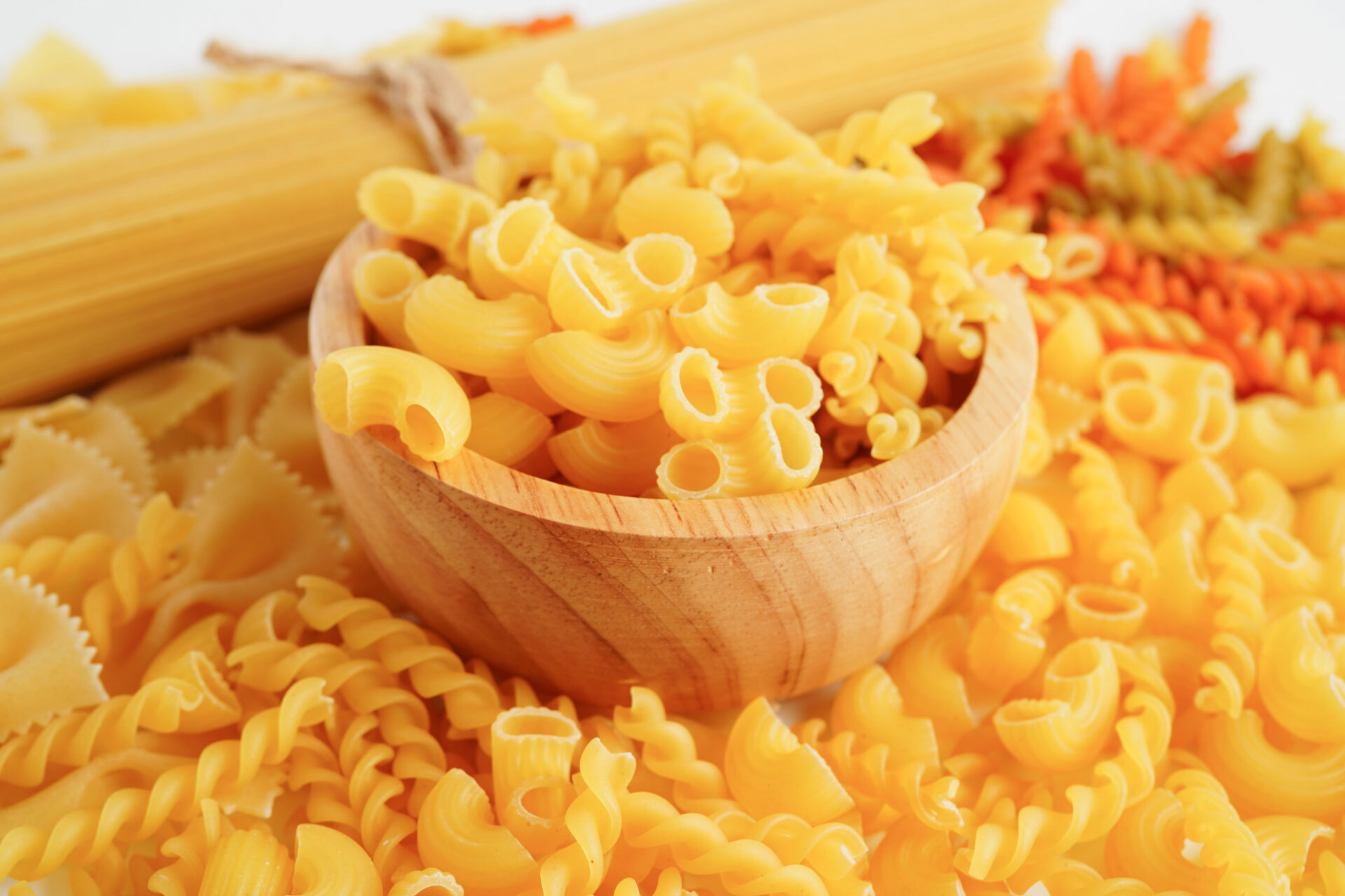 Dry pasta in a wooden bowl on the table in the kitchen
