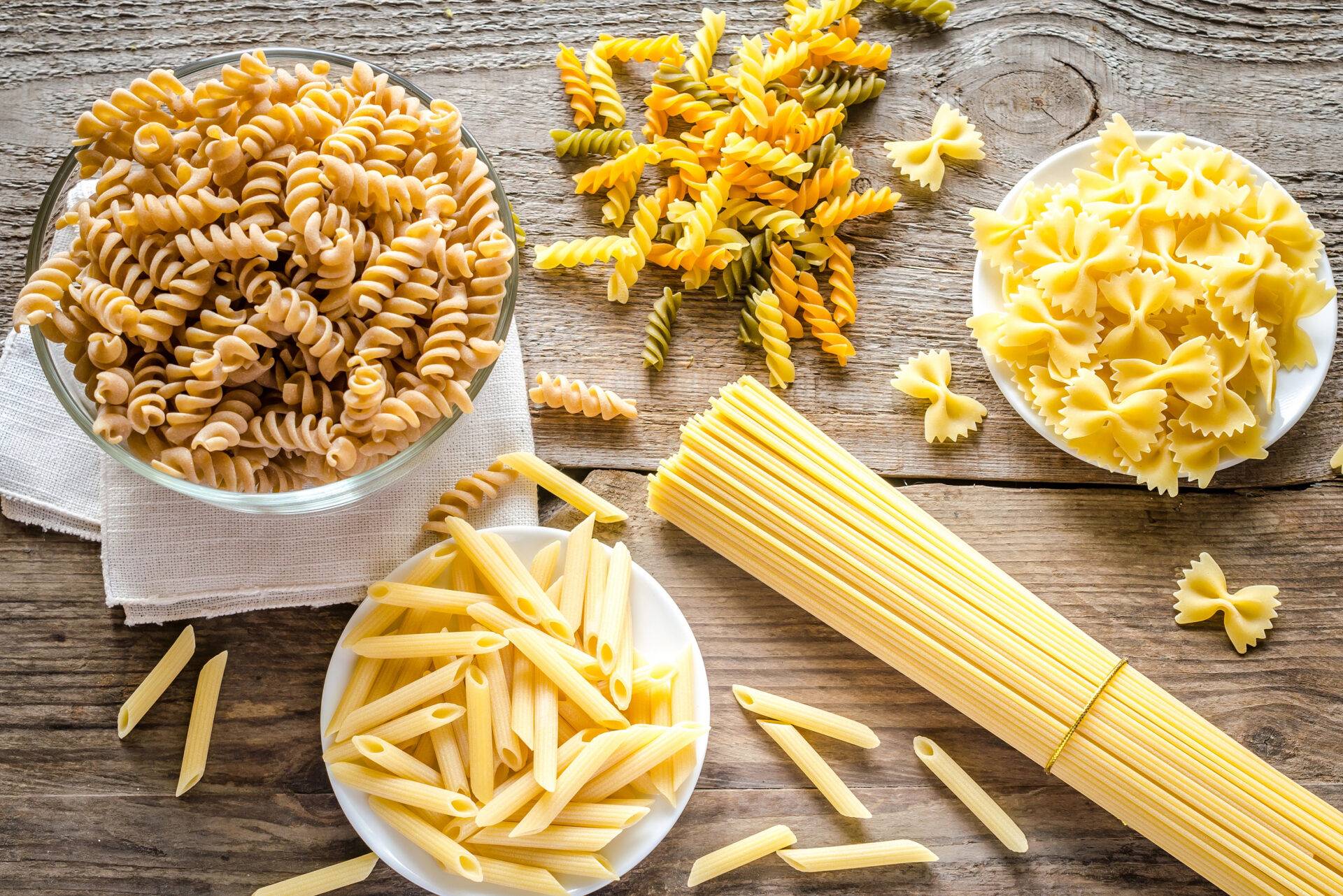 Different types of pasta like spaghetti and penne sitting on a table