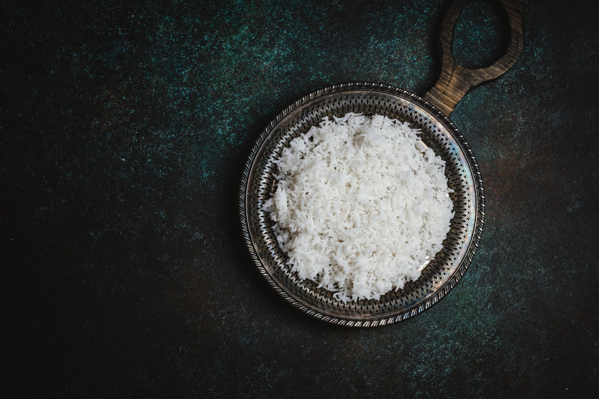 Jasmine rice in a stainless steel bowl on a dark table
