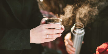Couple holding hot thermos for tea