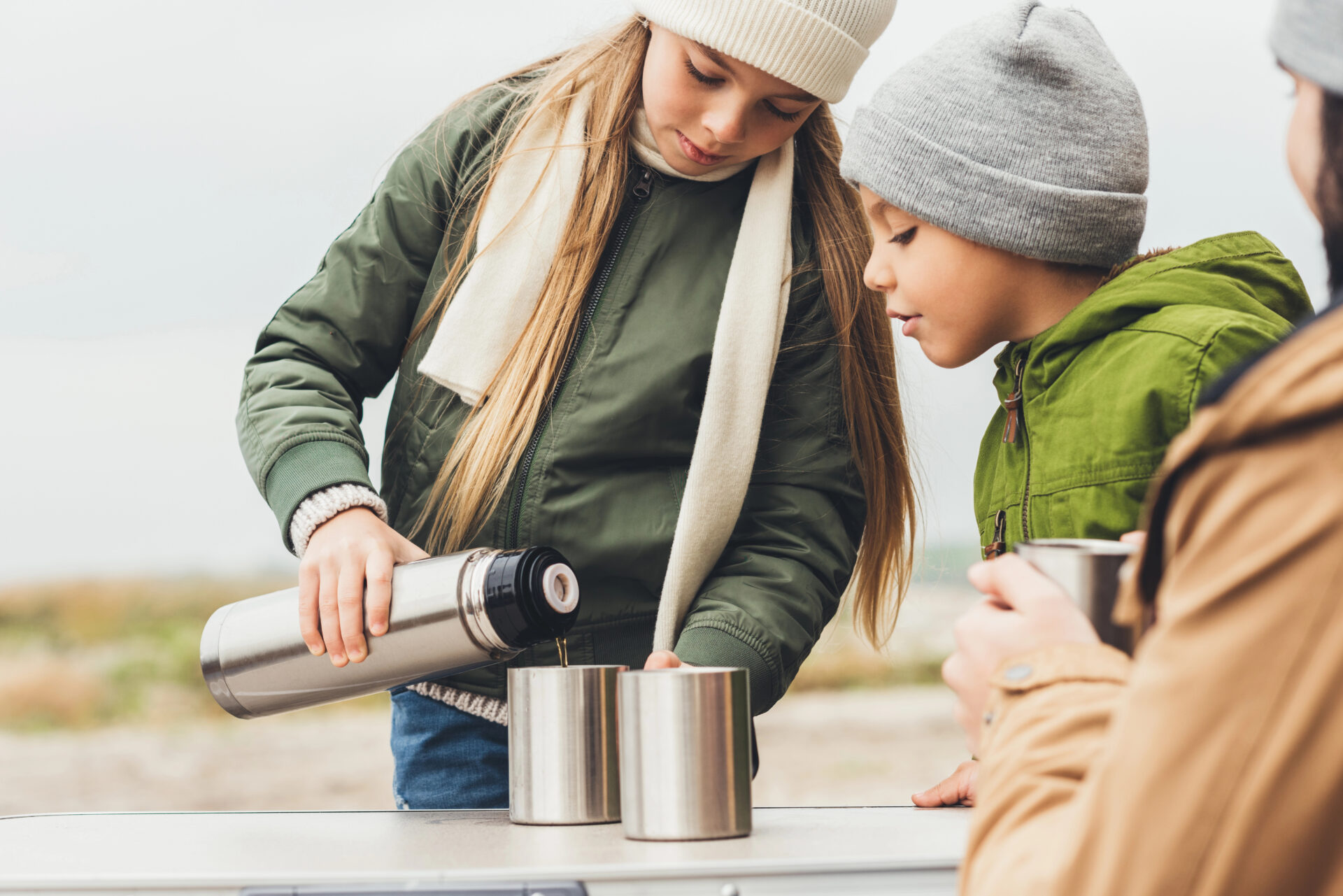 Mother and son pouring hot water from a thermos 