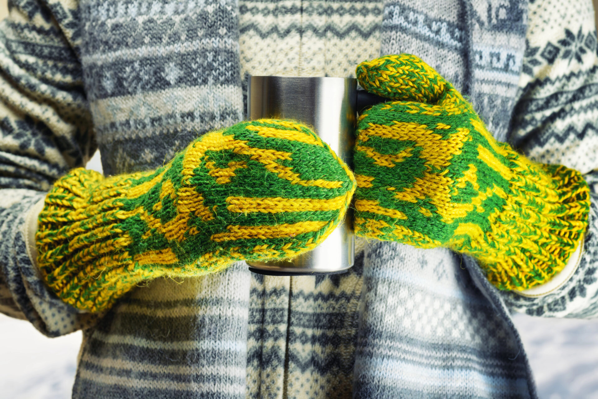 Hot beverage thermos held with mittens by woman