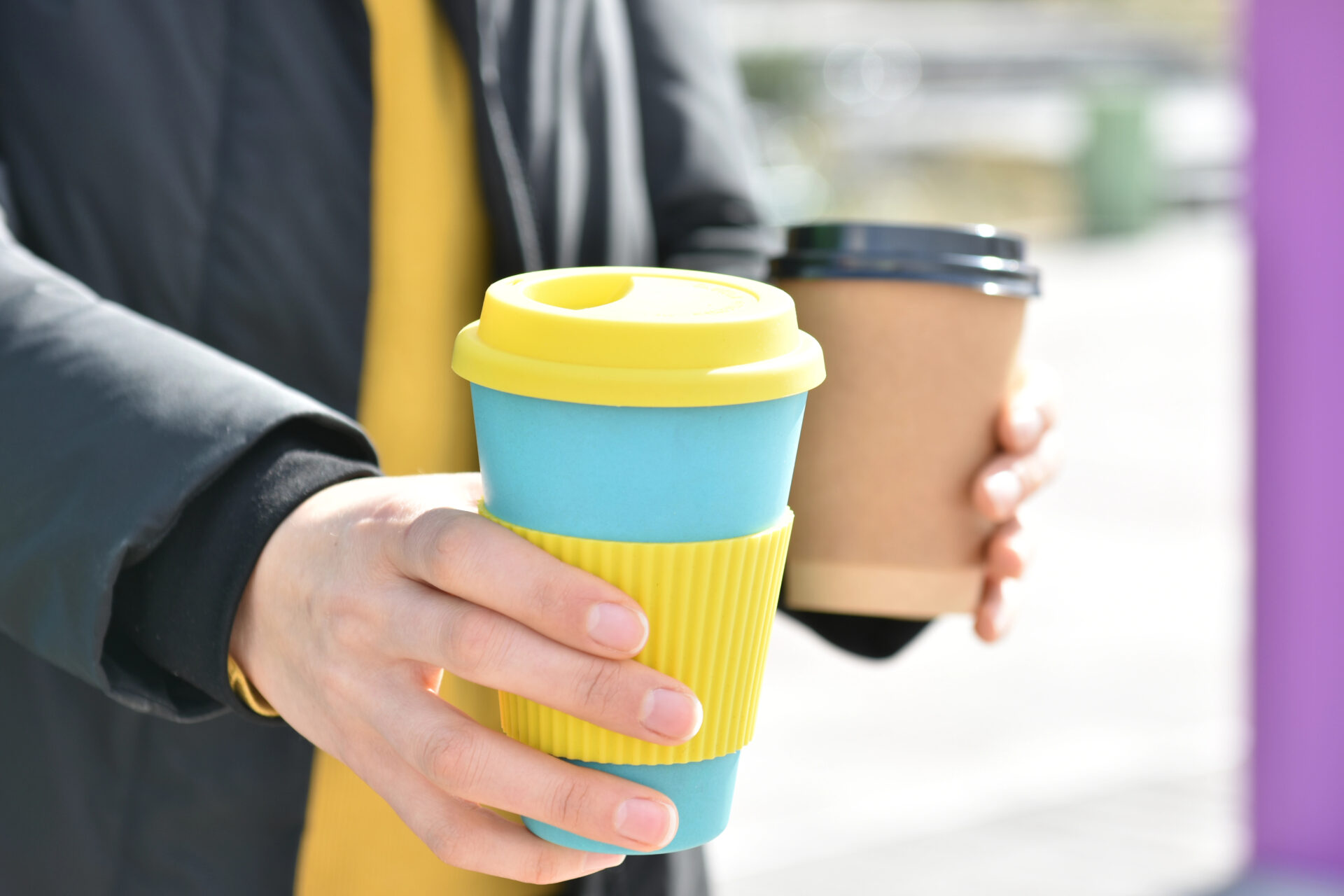Travel mugs being carried by a woman in the city
