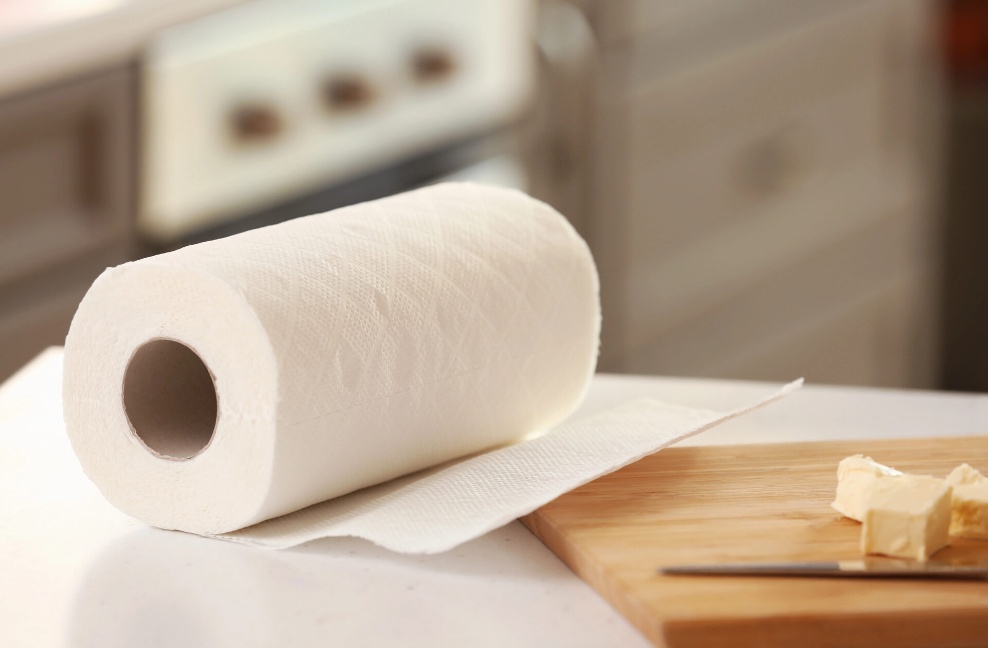 Roll of paper towels and wooden board with butter on kitchen table
