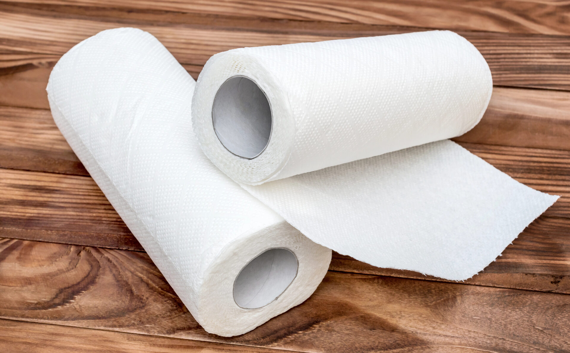 Two paper kitchen towels on the brown wooden table.