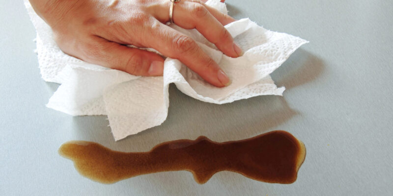 woman hand wiping spilled coffee with paper towel