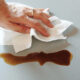 woman hand wiping spilled coffee with paper towel
