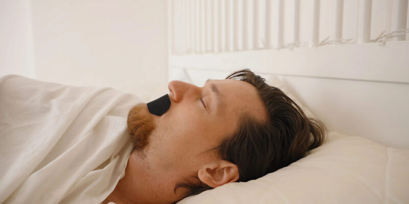 Man sleeping with mouth tape on his mouth