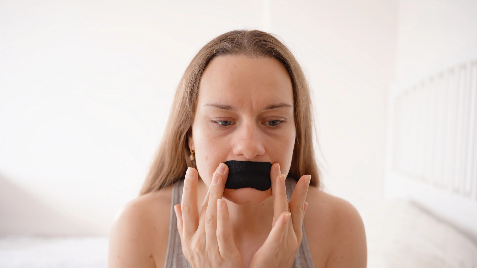 Woman putting on mouth tape 