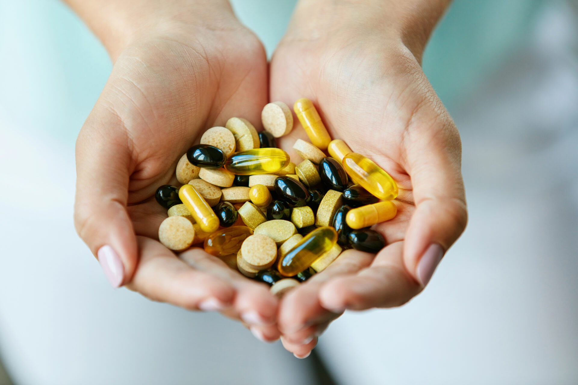 Vitamins And Supplements. Closeup Of Woman Hands Holding Variety Of Colorful Vitamin Pills. Close-up Handful Of Medication, Medicine Tablets, Capsules. 
