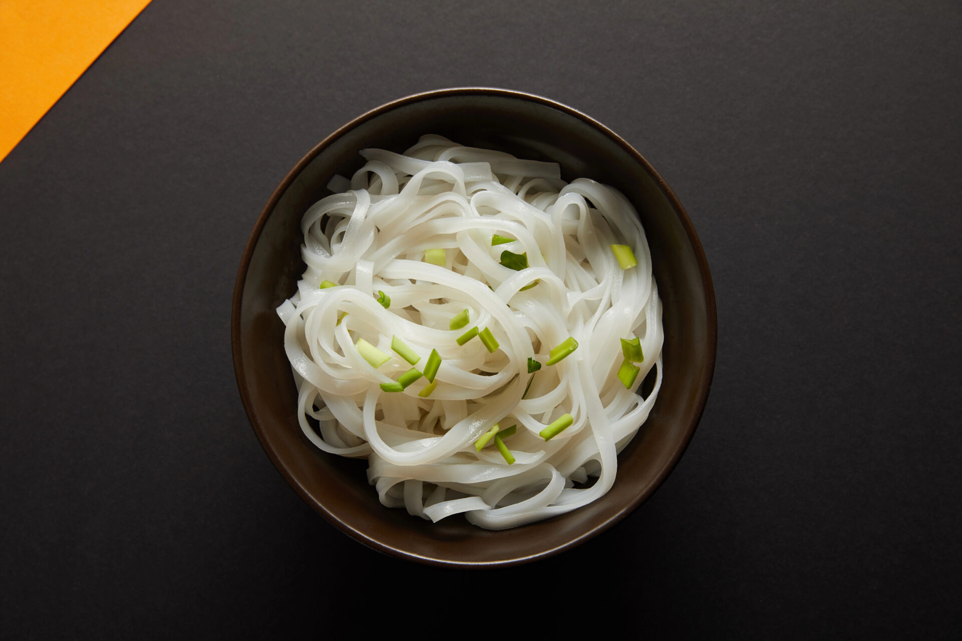 Rice Noodles with spring onions on a dark table