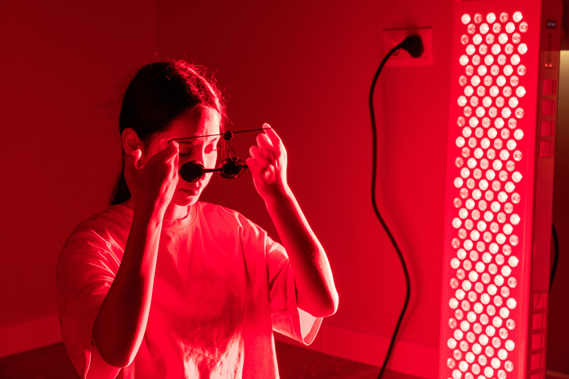 A young woman wearing protective glasses while seated during red light therapy