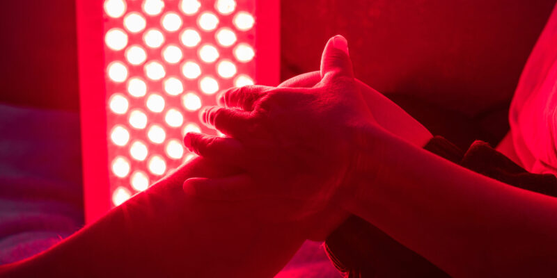 Closeup of sore leg of a person treating with the red light therapy panel