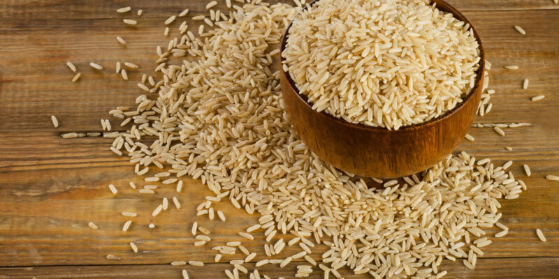 Uncooked brown rice in a wooden bowl. Selective focus