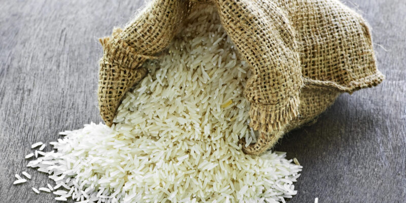 Raw long grain white rice grains in burlap bag