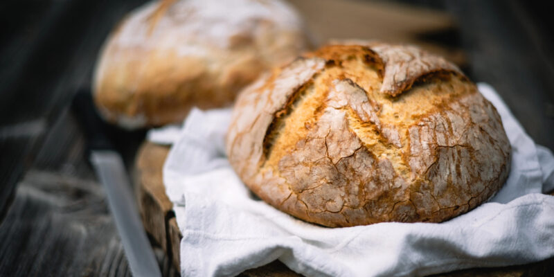 Traditional leavened sourdough bread with rought skin on a rustic wooden table. Healthy food photography