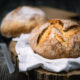 Traditional leavened sourdough bread with rought skin on a rustic wooden table. Healthy food photography