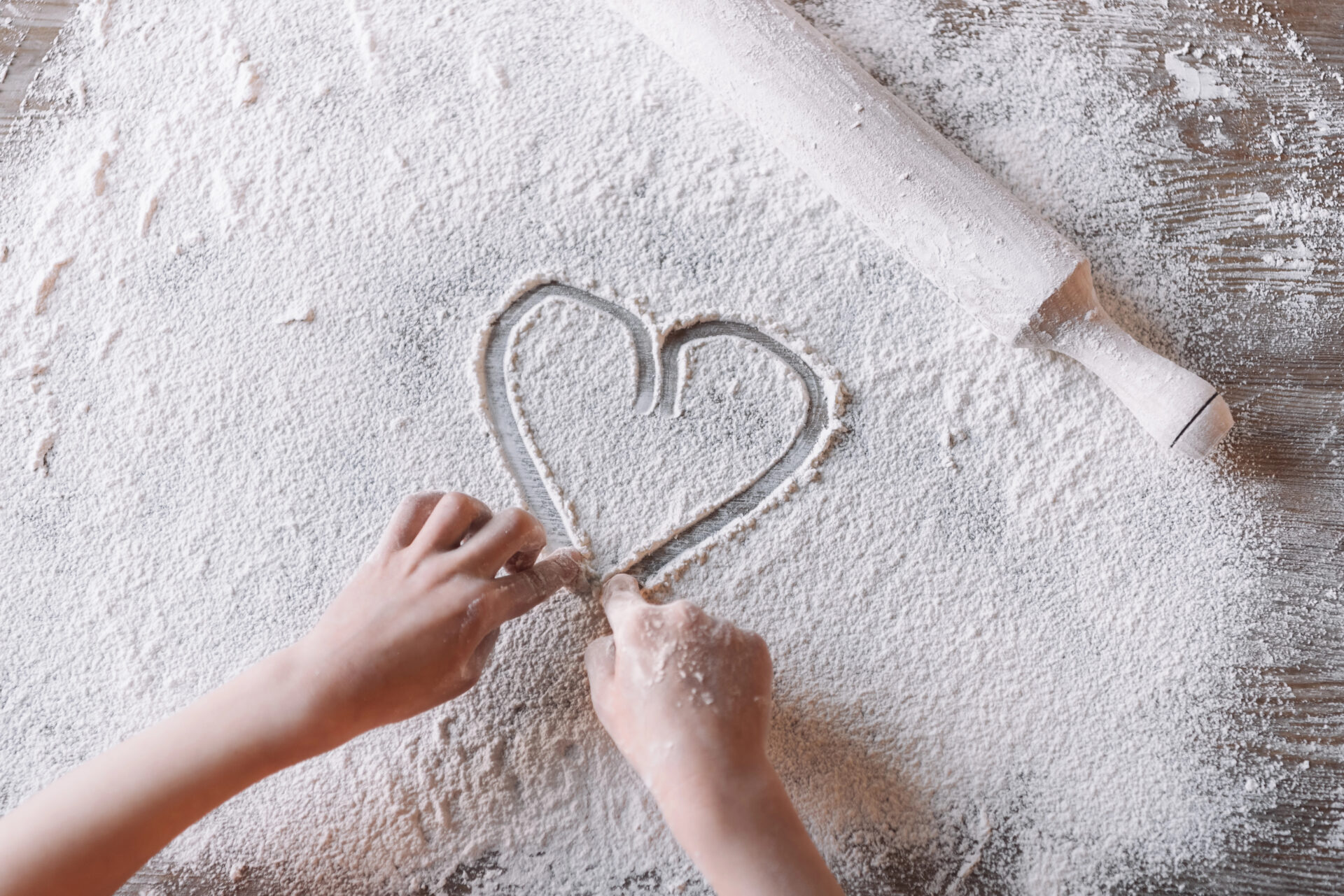 child makes heart in flour on the table
