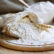 Flour in burlap bag on cutting board and wooden table background