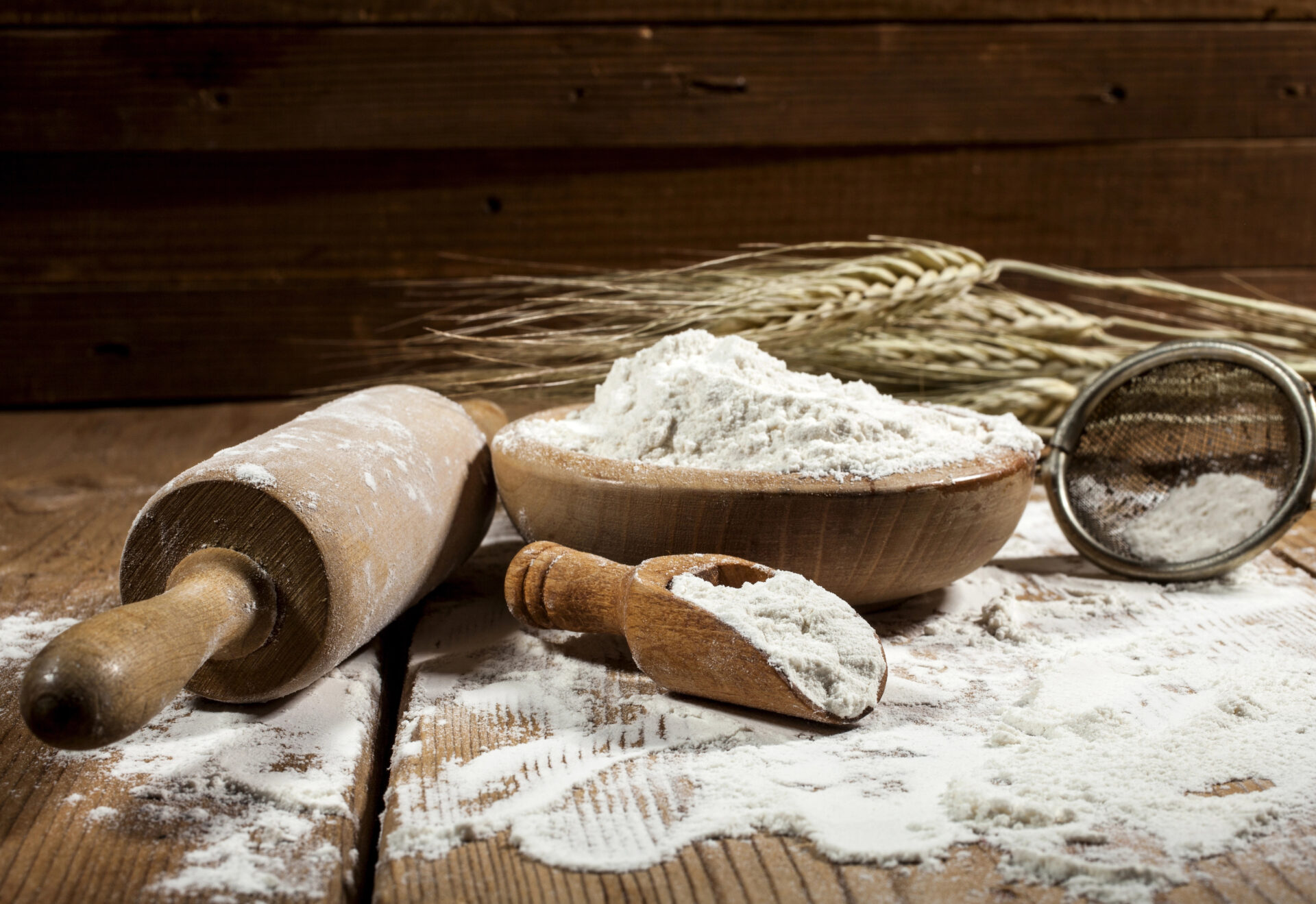 Flour and kitchen utensils on wooden background.