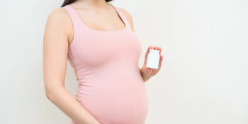 Pregnant woman holding prenatal vitamins in her hand
