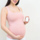 Pregnant woman holding prenatal vitamins in her hand