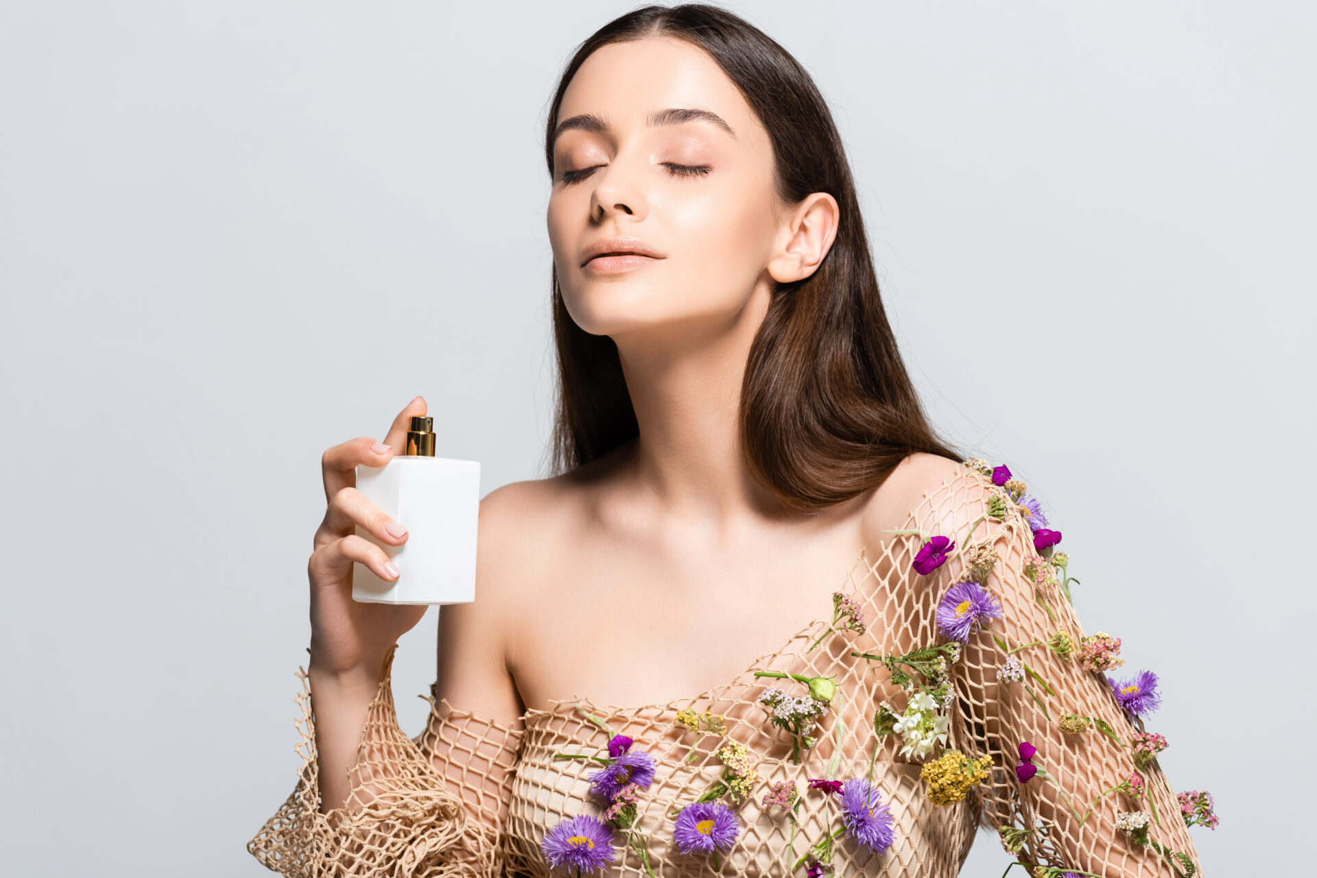 Woman spraying fragrance on her body while wearing flowers on her outfit