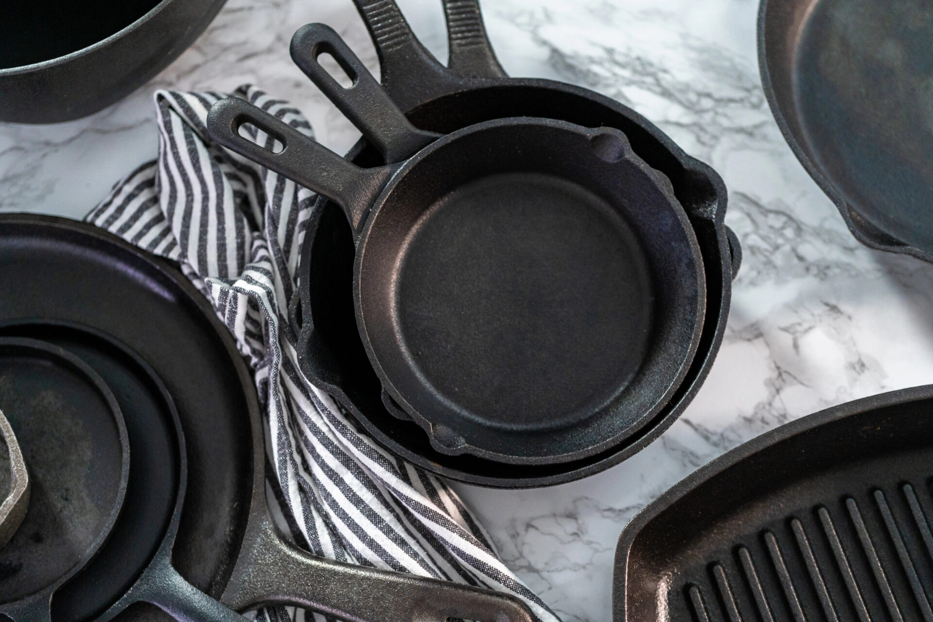 Variety of cast iron frying pans on a marble background
