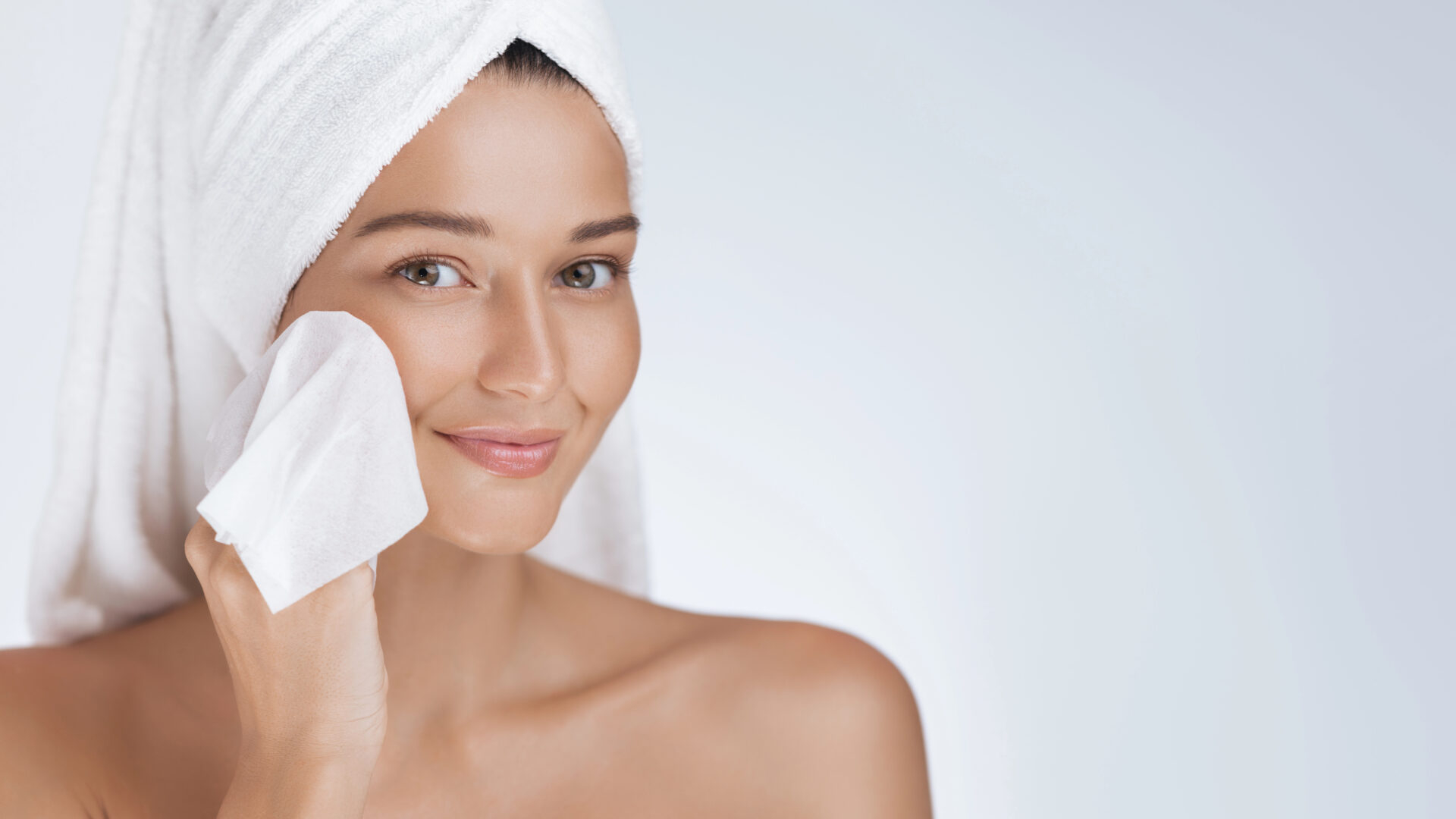 Woman who just got out of the shower cleaning face with makeup remover wipe